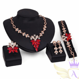 Clear crystal and red stone gold jewelry set with necklace, earrings, and bracelet on black display