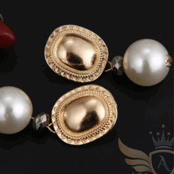 Close-up of luxe oval pearl drop earrings with gold oval top and pearl drop