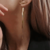 Gold long drop chain earrings on model’s ear